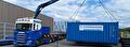 Scania met laadkraan tilt een container op de dieplader