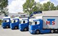 Vier vrachtauto’s van Mandema Transport naast elkaar, met de kraanwagen